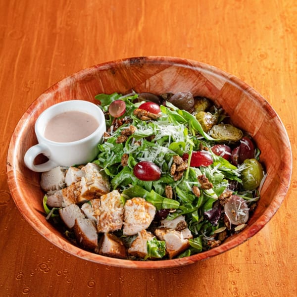 Reunion BBQ's salad with grilled chicken, greens, grapes, brussels sprouts, nuts, and dressing.