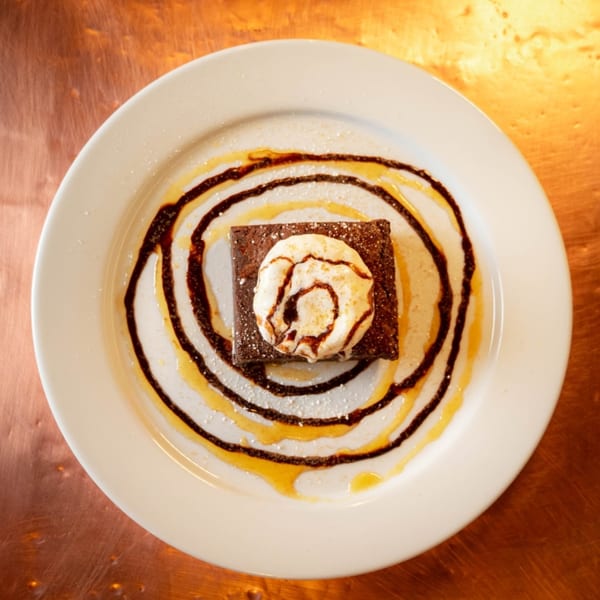 Reunion BBQ's brownie dessert, topped with whipped cream, chocolate, and caramel drizzle on a white plate.