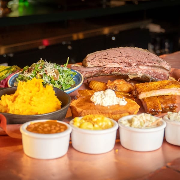 A Reunion BBQ platter with brisket, ribs, cornbread, mashed potatoes, salad, and side dishes.
